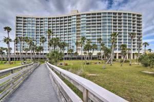 a boardwalk in front of a large building with palm trees at Heated Pool and Beach View Galveston Resort Condo! in Galveston