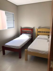 two beds in a small room with a window at Quiosque 2 in Joanópolis