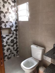 uma casa de banho com um WC branco e uma janela em Quiosque 2 em Joanópolis