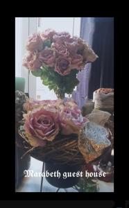 札格雷布的住宿－馬拉貝斯旅館，一张桌子上满是粉红色玫瑰的花瓶