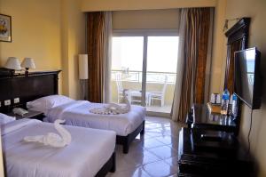 a hotel room with two beds with swans on them at Magic Beach Hotel Hurghada in Hurghada +103 photos