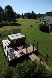 a wooden deck with a house in a field at Auberge Godard in Nominingue