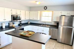 a kitchen with white cabinets and a stainless steel refrigerator at South Padre Island Oasis with Pool Walk to Beach! in South Padre Island