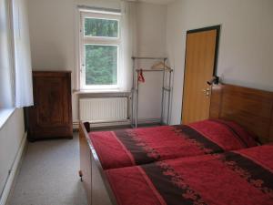 a bedroom with a red bed and a window at Hexenstieg House Lerbach in Osterode