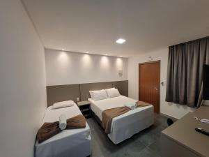 Habitación de hotel con 2 camas y escritorio en Hotel Conchas, en Penha