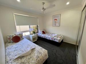 1 dormitorio con 2 camas, ventana y falda en Lux in Bundy - Wifi, AC, Netflix and comfort, en Bundaberg