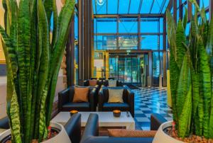a lobby with couches and plants in a building at nestor Hotel Stuttgart-Ludwigsburg in Ludwigsburg