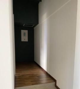 an empty hallway with a white wall and wood floors at Apartamento cerca al centro comercial Santafé A105 By Roots Rentals in Medellín