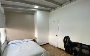 a bedroom with a bed and a white wall at Apartamento cerca al centro comercial Santafé A105 By Roots Rentals in Medellín