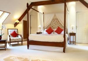 a bedroom with a canopy bed with red pillows at Manoir De Kertalg in Moëlan-sur-Mer