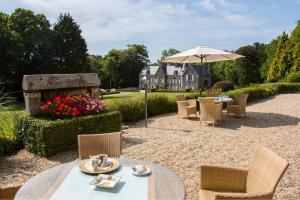 a patio with a table and chairs and an umbrella at Manoir De Kertalg in Moëlan-sur-Mer