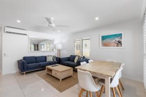 a living room with a blue couch and a table at Bella Casa Noosa in Noosa Heads