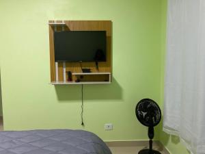 a bedroom with a flat screen tv on a green wall at Suítes Acolhedoras da Diva in Alto Paraíso de Goiás