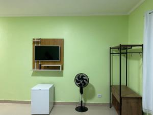 um quarto com uma ventoinha e uma parede verde em Suítes Acolhedoras da Diva em Alto Paraíso de Goiás