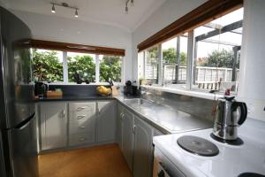 a kitchen with white cabinets and a sink and windows at Kingwell Cottage - New Plymouth Holiday Home in New Plymouth