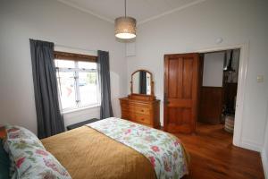 um quarto com uma cama, uma cómoda e uma janela em Kingwell Cottage - New Plymouth Holiday Home em New Plymouth