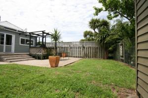 a backyard of a house with a fence at Kingwell Cottage - New Plymouth Holiday Home in New Plymouth