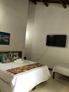 a bedroom with a bed and a flat screen tv at Pousada Flor do Arraial in Arraial d'Ajuda