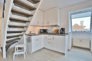 a kitchen with white cabinets and a spiral staircase at Villa Meeresstrand Villa Meeresstrand Appartement 10 in Haffkrug
