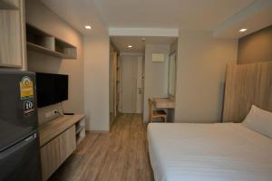 una habitación de hotel con cama y televisor de pantalla plana en Baan Tanwa - MRT Ratchadapisek Exit 1 or 2, en Bangkok