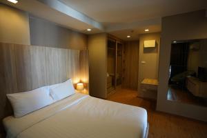 a bedroom with a white bed and a bathroom at Baan Tanwa - MRT Ratchadapisek in Bangkok