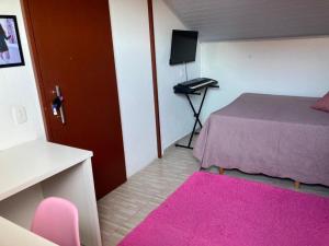 Habitación pequeña con cama y alfombra rosa en Enseada encantada, en Porto Belo