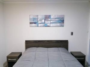 a bedroom with a bed with two tables and a painting at Por días Acogedor Departamento amoblado vista La Herradura in Coquimbo