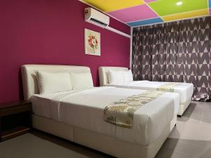 duas camas num quarto com paredes roxas em Cassia Inn Kuching em Kuching