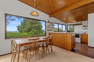 Te Whare Rākau - Paihia Holiday Home في بيهْيا: مطبخ مع طاولة وكراسي ونافذة كبيرة