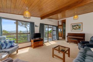 Te Whare Rākau - Paihia Holiday Home في بيهْيا: غرفة معيشة فيها تلفزيون وبيانو