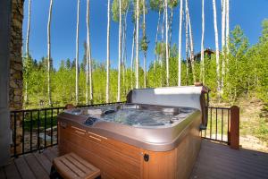 a hot tub on a deck with trees in the background at Leland Creek Home in Winter Park