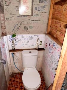 a toilet in a bathroom with writing on the wall at Syalala bnb in Timuran
