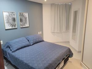 - une chambre avec un lit bleu et deux photos sur le mur dans l'établissement Espetacular Flat Miramar 3, à João Pessoa