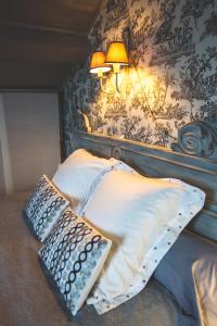 łóżko z 2 poduszkami i lampką na ścianie w obiekcie Au Bien Venu w mieście Noé