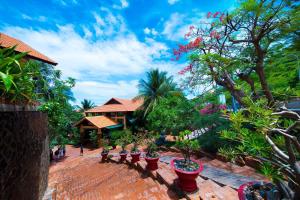 a garden with potted plants on a brick path at Hon Rom Central Beach Resort in Mui Ne