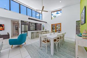 a dining room and kitchen with a white table and chairs at Hilltop Views - Cannonvale in Airlie Beach