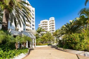 a street with palm trees and a tall building at ULTIQA Burleigh Mediterranean Resort in Gold Coast