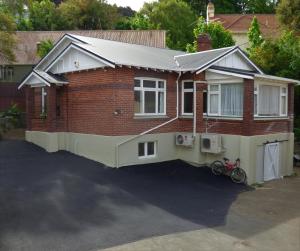 uma casa de tijolos com uma bicicleta estacionada em frente em Sahara Deluxe Studios em Dunedin