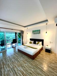 a bedroom with a large bed and a large window at Khaosok Good view Resort - SHA PLUS in Khao Sok