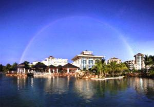 a rainbow over a resort with a pool of water at The Empire Brunei in Bandar Seri Begawan