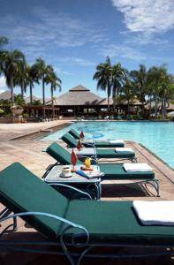 a row of green lounge chairs next to a swimming pool at The Empire Brunei in Bandar Seri Begawan