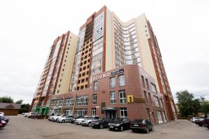 duży budynek z samochodami zaparkowanymi na parkingu w obiekcie The First Apart Hotel w mieście Tomsk