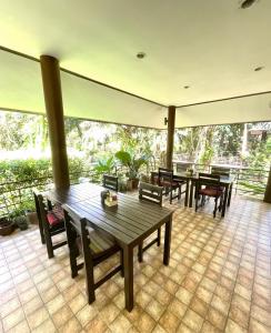 eine Terrasse mit Tischen und Stühlen auf einem Fliesenboden in der Unterkunft Khaosok Good view Resort - SHA PLUS in Khao Sok