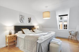 a white bedroom with a large bed and a chair at Sanders Leaves - Precious Two-Bedroom Penthouse In Downtown Copenhagen in Copenhagen
