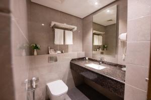 un bagno con lavandino, water e specchio di ROZANA HOTEL a Mascate
