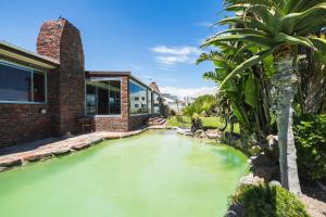 a large pool of water in front of a house at Melkbos Beach Lodge in Cape Town