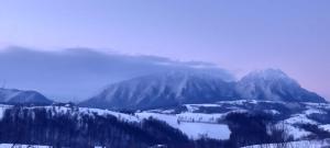 una montaña cubierta de nieve con un lago delante de ella en Conacul Elenei en Poiana Mărului