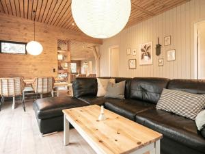 een woonkamer met een zwarte leren bank en een tafel bij 10 person holiday home in Vinderup in Vinderup