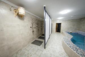 a bathroom with a swimming pool and a walk in shower at AS Inn Hotel in Karagandy