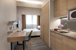 a hotel room with a bed and a kitchen with a desk at Modena by Fraser Hong Kong in Hong Kong